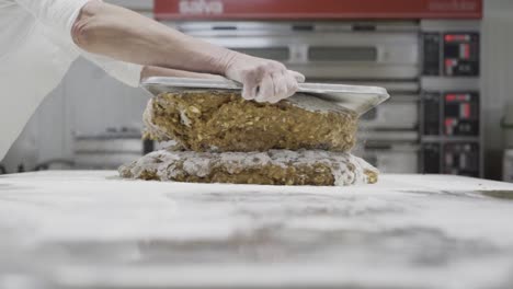 slow motion panning shot of a dough for sweets being stacked and portioned with a tablet by a baker in a sweets factory in medina sidonia