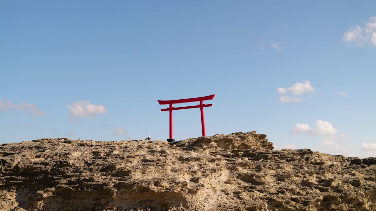 vista minimalista de la puerta roja japonesa en la parte superior de las rocas contra el cielo azul