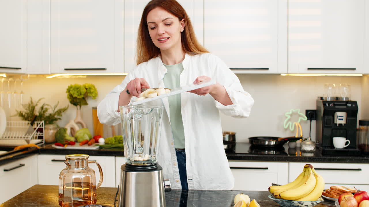Donna di mezza età prepara un frullato di banane nella cucina di casa per una colazione sana e per la perdita di peso.