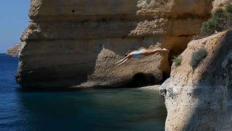 woman cliff diving into blue ocean water