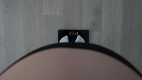 pregnant woman standing on a scale pulling out her tummy