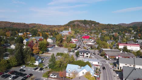 drone approach saint-sauveur town within les pays-d'en-haut regional county municipality, quebec canada , mountain covered in orange foliage during fall season clear sky sunshine