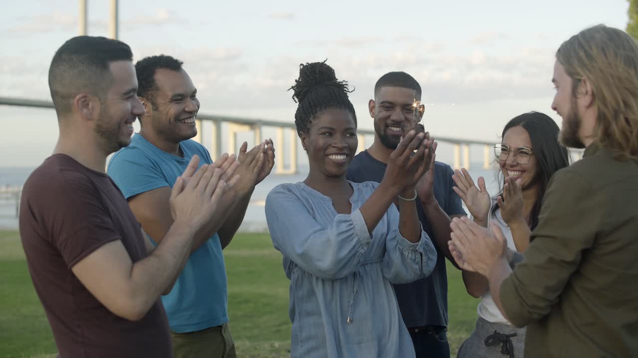 amigos sonrientes felicitando a una joven por su cumpleaños