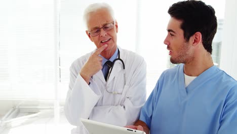 médico masculino y compañero de trabajo discutiendo sobre una tableta digital