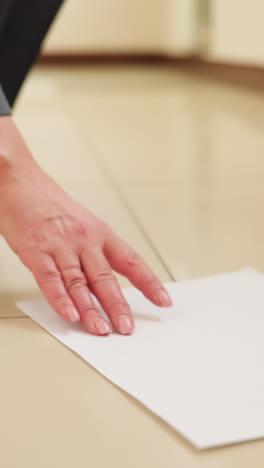 scattered documents lie on tiled floor near businesswoman s feet in hallway, suggesting papers were accidentally dropped during walk, conveying urgency, workplace stress, or unexpected interruption