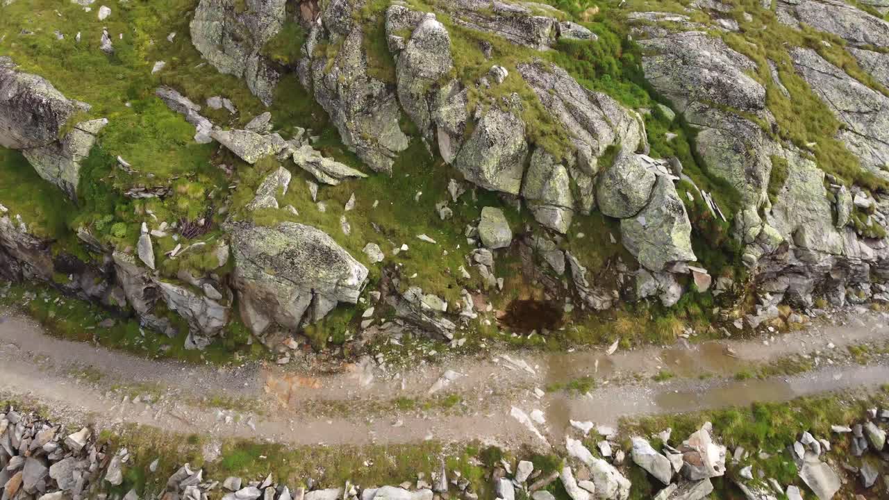 오스트리아 카른텐의 알프스 산맥에서 돌이와 몇 개의 눈이로 둘러싸인 집을 드러내기 위해 돌이를 기울이는 드론