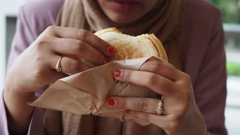 close-up of a person holding and eating a sandwich