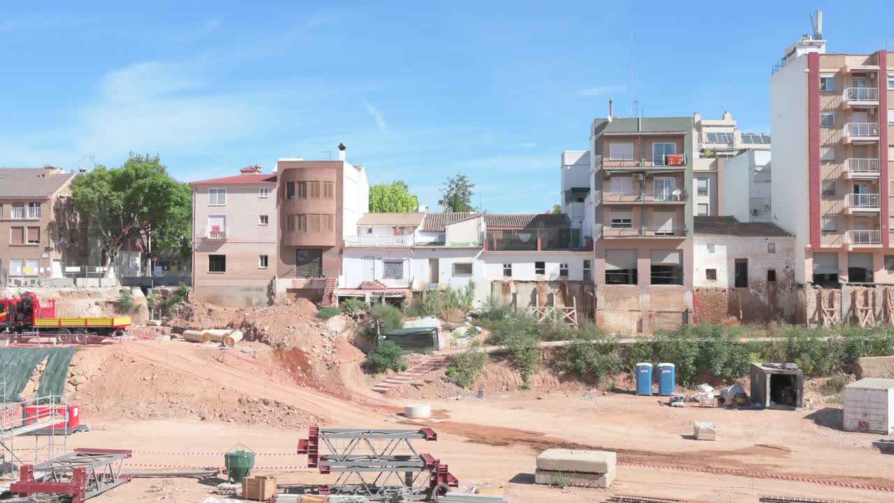 Urban regeneration project showing heavy machinery transforming a ravine into a construction site, one year after the DANA floods