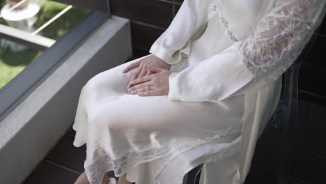 bride in a lace trimmed gown sitting calmly with hands folded on her lap before the ceremony