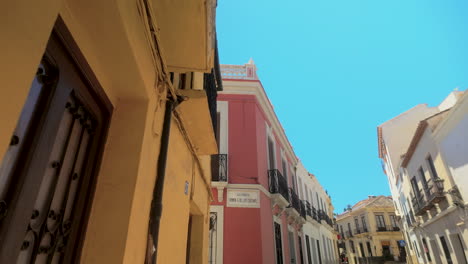 low-angle view of colorful buildings in ronda, spain, with intricate balconies and a clear blue sky