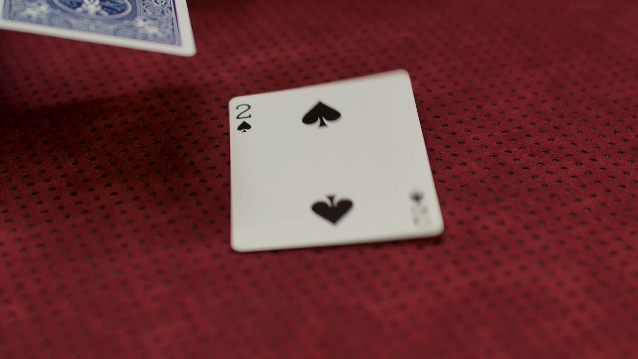 Slow motion closeup of a card dealer revealing a two of spades on the game table