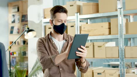 caucasian designer man using a tablet in a fashion clothing store