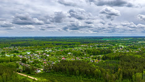 clouds moving above rural residential area and forest landscape under cloudy spring sky