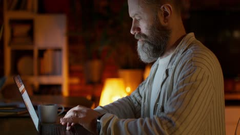 hombre trabajando en la computadora portátil por la noche en casa