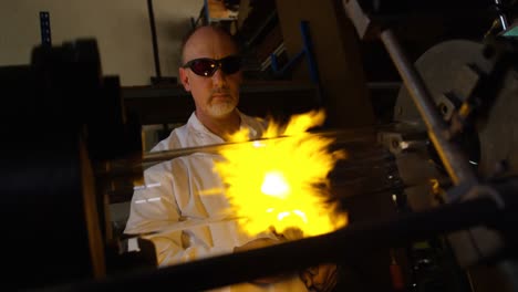 front view of mature male worker blowing glass in glass factory 4k