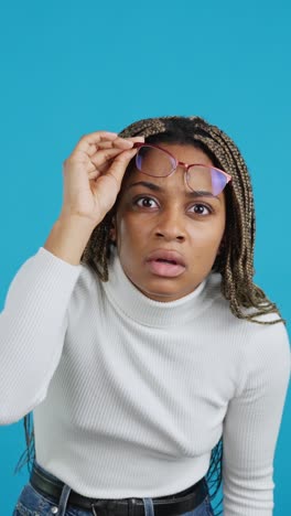 confused woman adjusting her glasses on a blue background