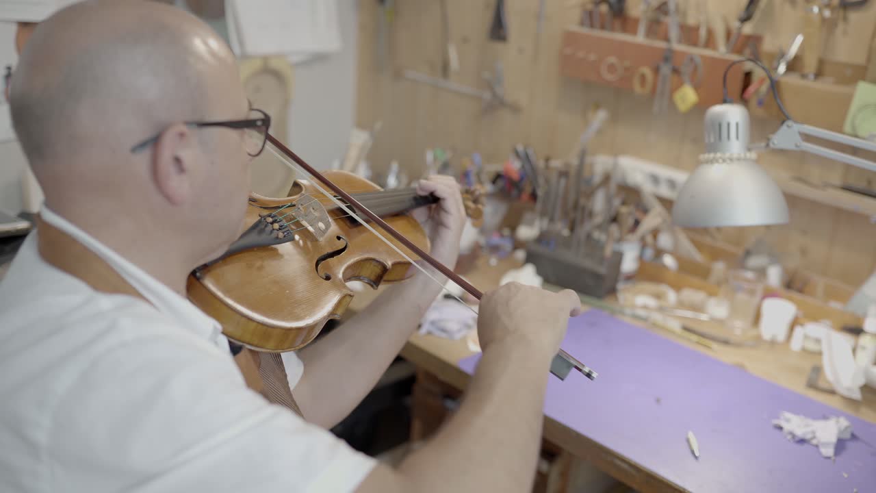 maestro luthier che suona il violino in officina
