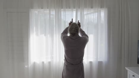 Senior-man-drawing-the-curtains-at-home