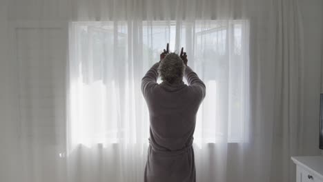 senior man drawing the curtains at home