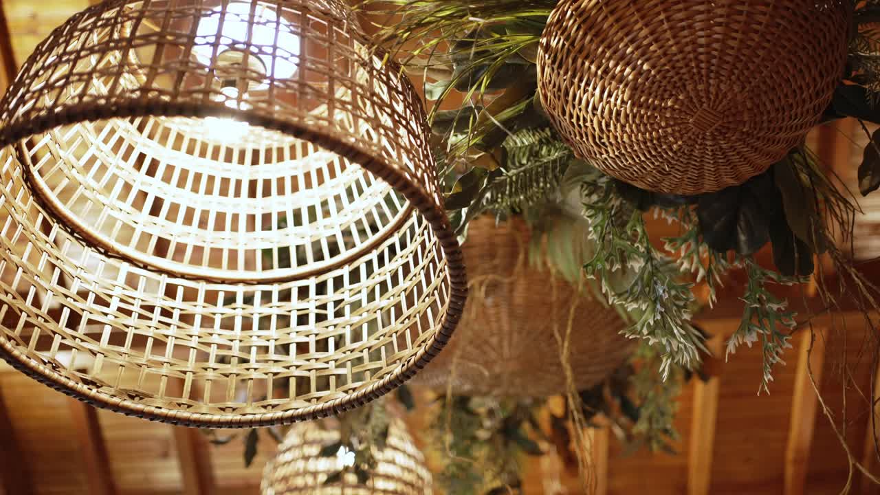Handwoven wicker pendant lights with greenery in a rustic wooden ceiling