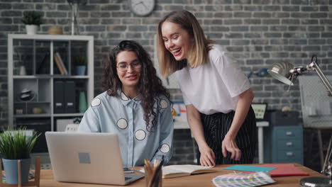 two women collaborating on a laptop in a modern office