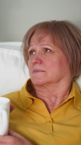 una anciana triste descansa en la cama en casa. una nieta cuidadosa le trae una taza de agua a la abuela. ayudando a las personas mayores en un primer plano familiar amistoso