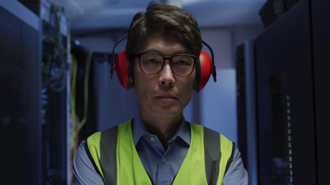 Portrait of asian male it technician wearing headphones by computer server