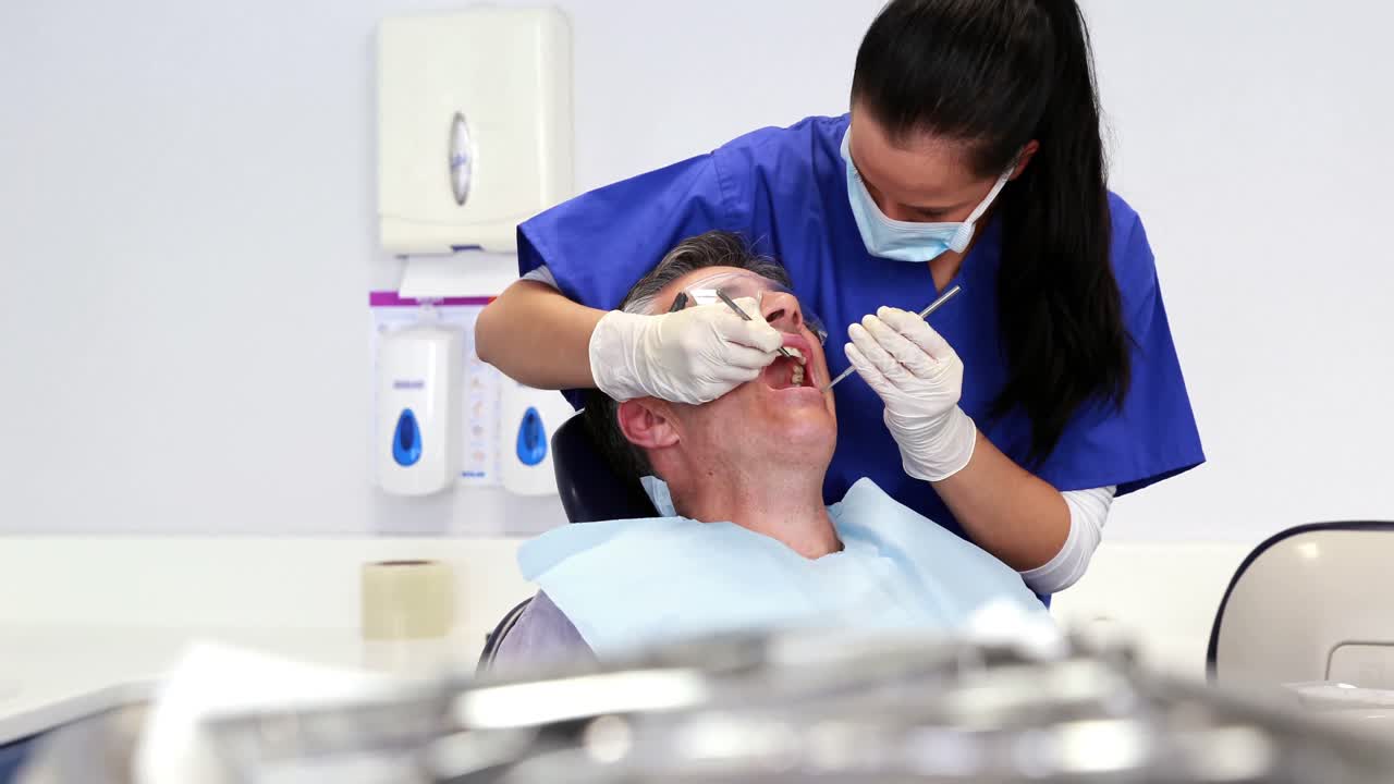 Dentista che esamina i denti dei pazienti nella sedia dei dentisti