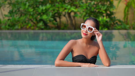 Una-Mujer-Hermosa-Que-Se-Relaja-En-La-Piscina-De-Un-Resort-Ajusta-Sus-Gafas-De-Sol-Para-Tener-Una-Mejor-Vista-De-Su-Entorno