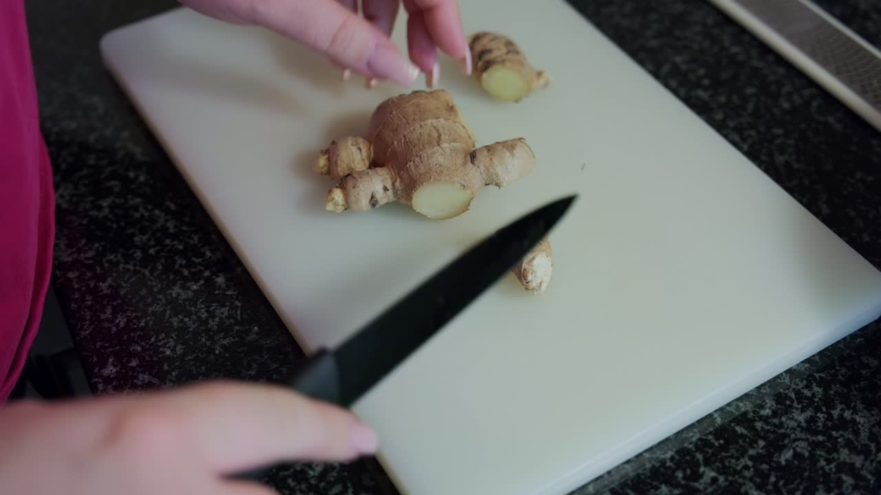 Woman's hands cutting ginger on a white board, interior