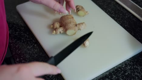 woman's hands cutting ginger on a white board, interior