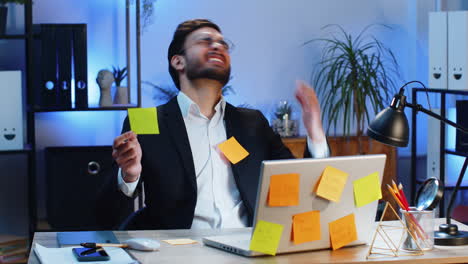 tired sad exhausted businessman working on laptop at office with many sticker tasks panic attack
