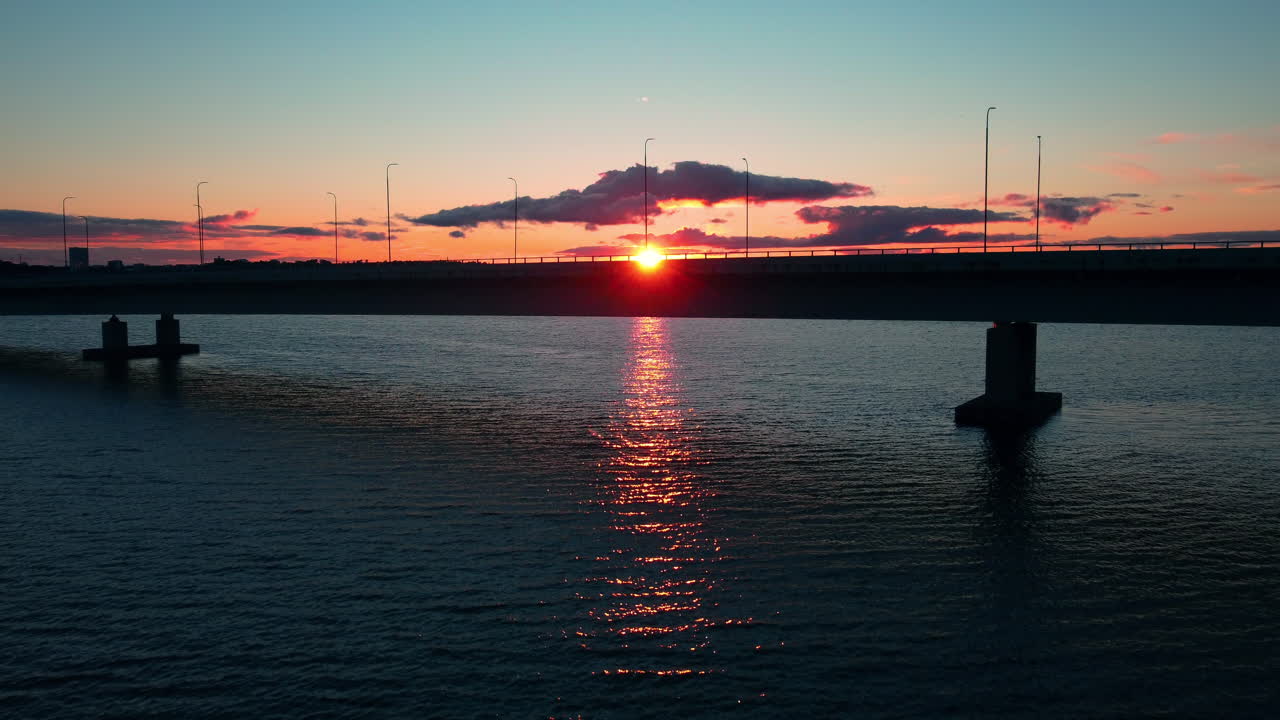 Aerial view of traffic on the Lapinlahti bridge with a colorful sunset background - ascending, drone shot