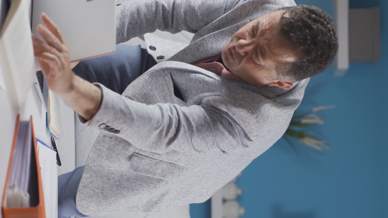 video vertical de un trabajador de oficina en casa un anciano encuentra lo que está buscando en la mesa.