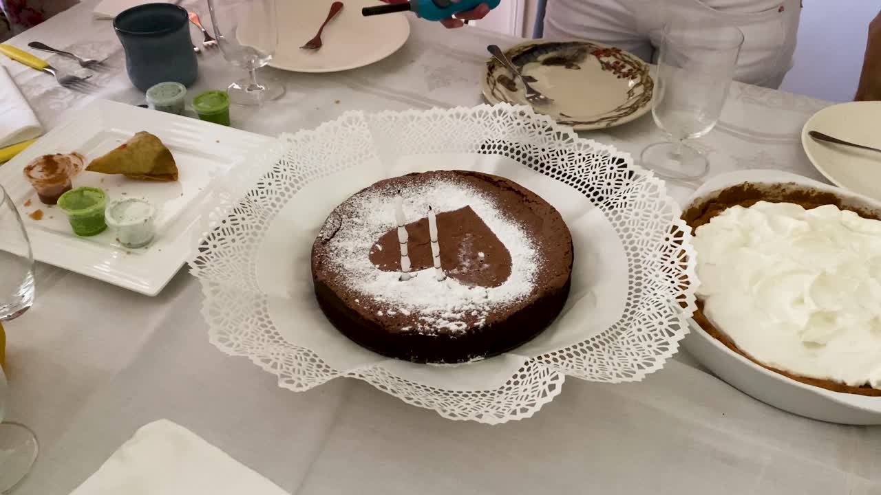 los miembros de la familia se reúnen para soplar las velas encendidas en un pastel en forma de corazón, compartiendo un momento alegre de celebración y unión