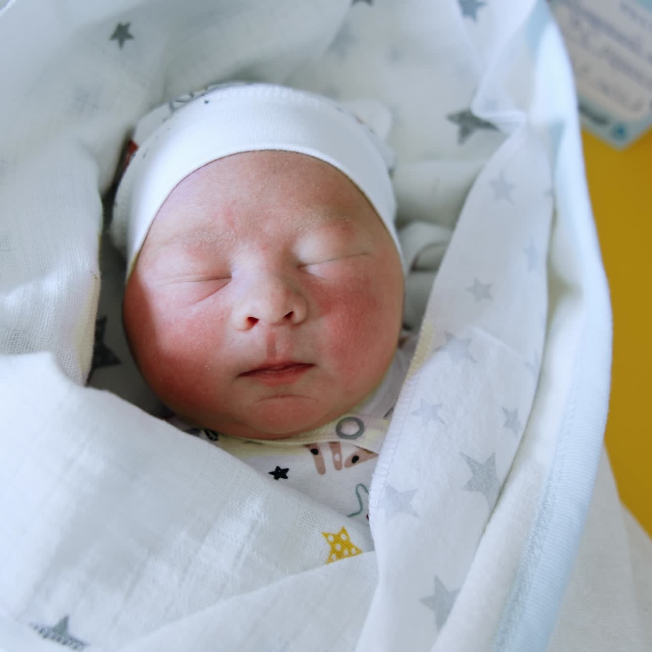 Un neonato carino dorme coperto da coperte. Un bambino adorabile fa l'occhiolino alla luce. Primo piano