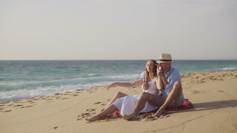 pareja sentada en cuadros en una playa de arena