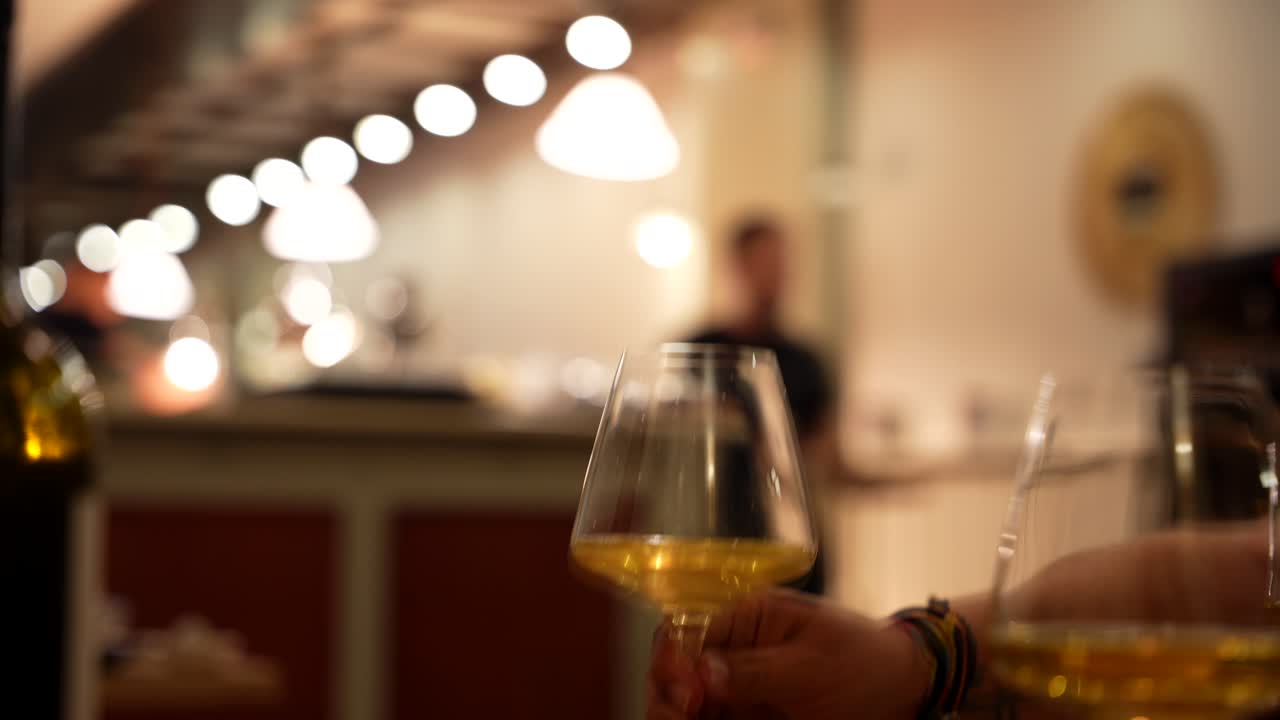 Dining customer grabs glass of white wine at restaurant. Closeup, selective focus, slowmo