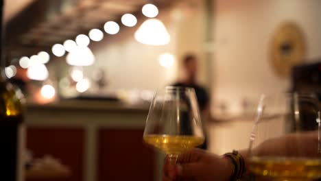 dining customer grabs glass of white wine at restaurant. closeup, selective focus, slowmo