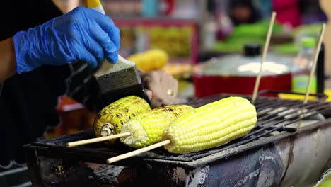 vendor grilling corn with seasoning at night market