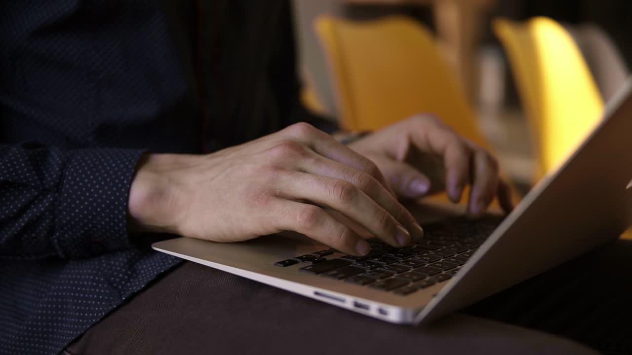 Male hands typing something on a laptop keyboard.