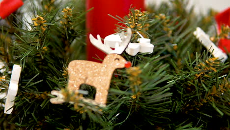 Red-candle-into-Christmas-tree-leaves,-xmas-event-decoration---macro-close-up-pull-out-shot