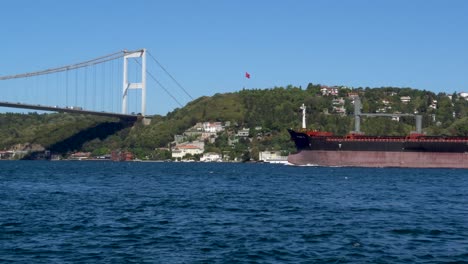 cargo ship passing under fatih sultan mehmet bridge, bosphorus, istanbul, turkey