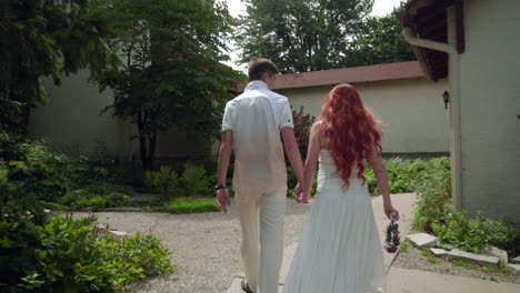 Rear-view-of-couple-walking-at-backyard-of-country-house