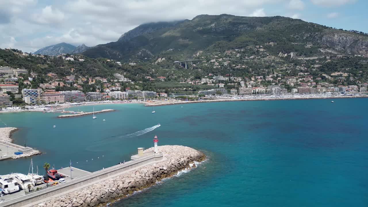 Faro e frangiflutti per il porto turistico a Mentone, Francia meridionale, ripresa aerea con panoramica a sinistra