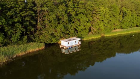 houseboat floating on a lake next to a forest during sunset in brandenburg, germany