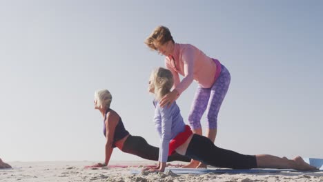 yoga teacher teaching yoga to senior women at the beach