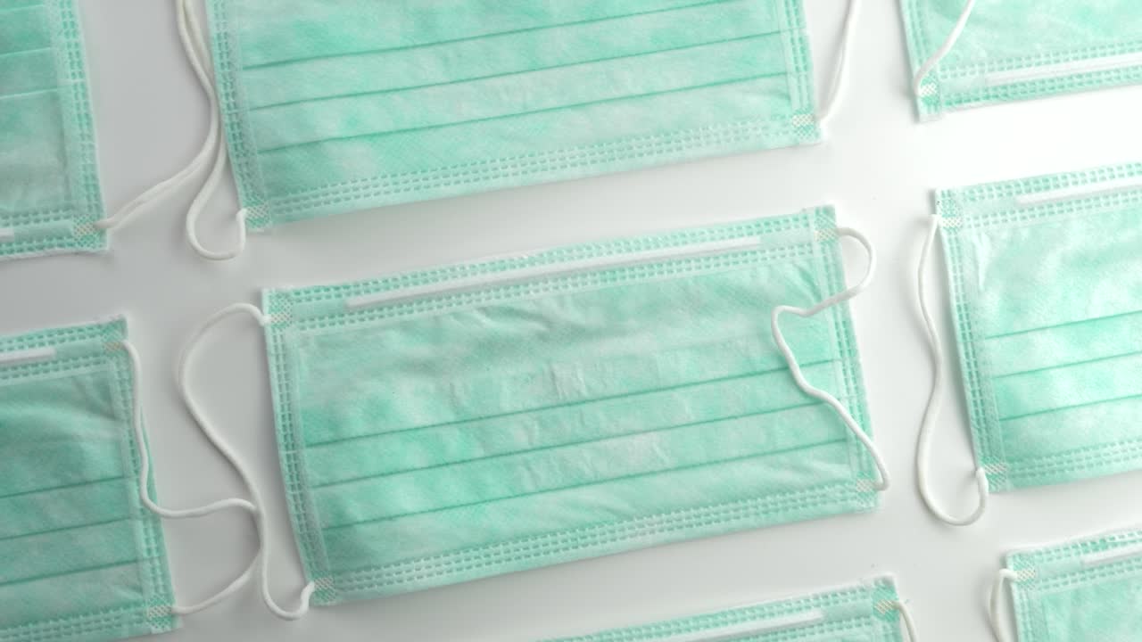 nuevas máscaras faciales quirúrgicas mostradas en filas sobre superficies planas - toma de rotación superior