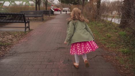 An-adorable-little-girl-in-a-pink-dress-running-outside-after-a-spring-rain---slow-motion