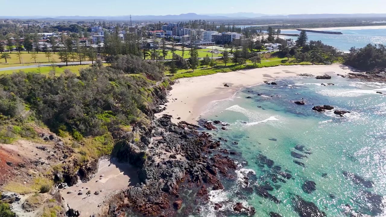 Vue aérienne en plongée de vagues océaniques turquoises s'écrasant contre des falaises rocheuses à Port Macquarie.